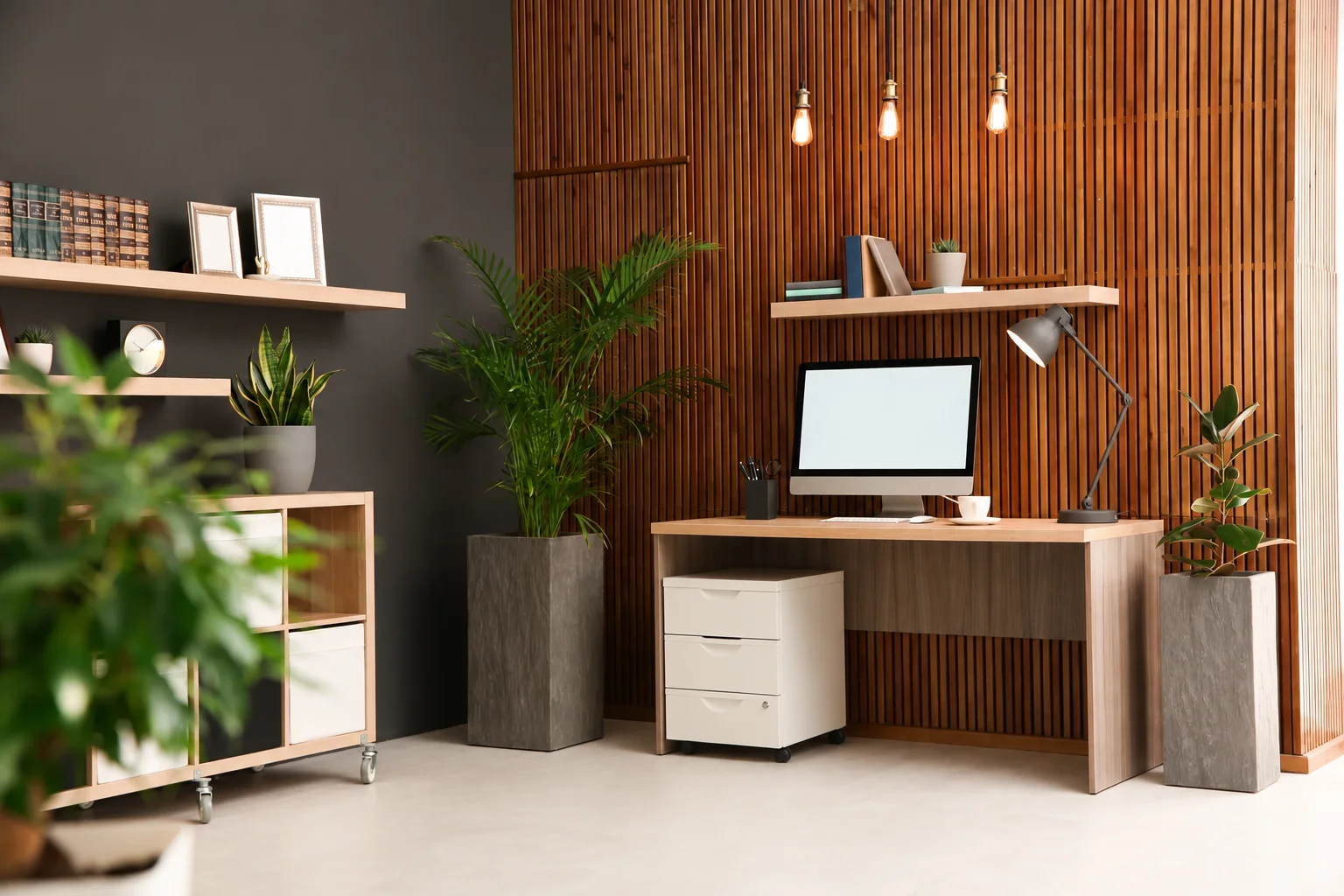 Home office with a slatted wood wall, a desk and plants, and no chair or rug